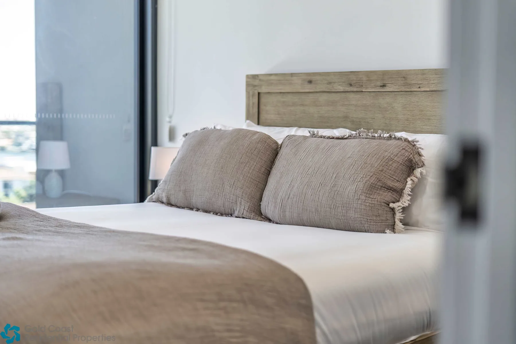 Un dormitorio con una cama bien hecha y una ventana grande.