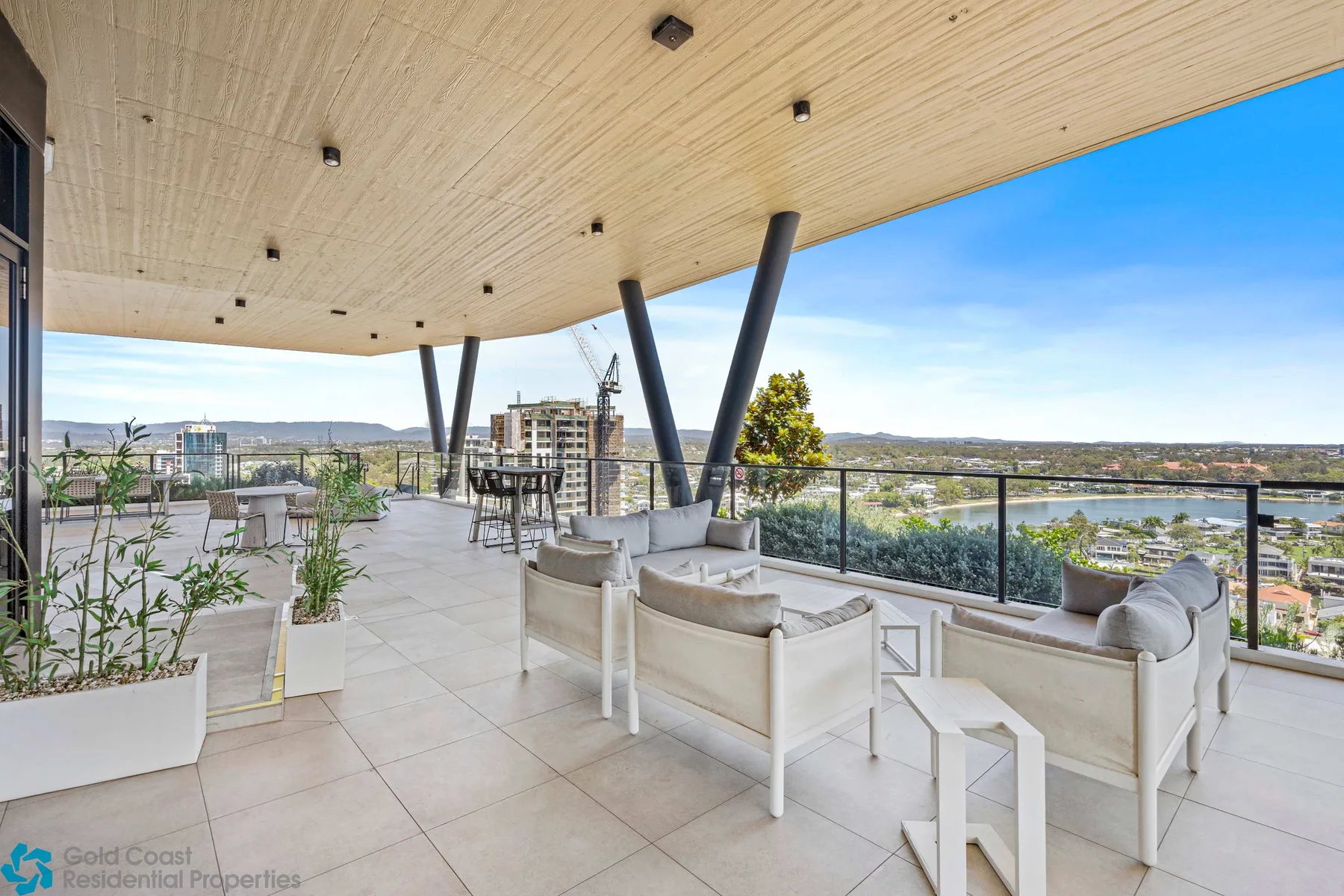 Una amplia terraza al aire libre tiene asientos junto a barandillas de vidrio y vistas de la ciudad.