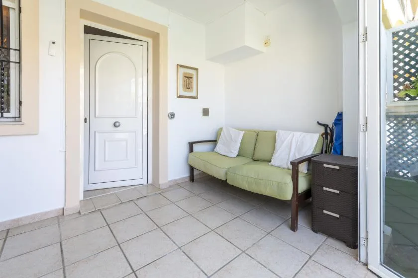 A small sitting area with a pale green couch beside a white door.