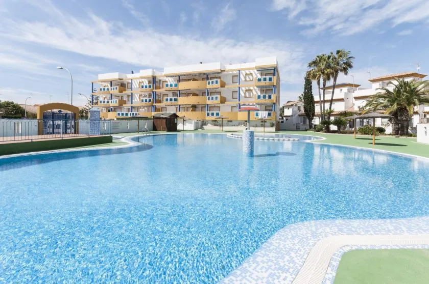 An outdoor swimming pool sits in front of a multistory building.