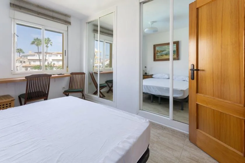 A bedroom with a bed, a window, and a small seating area.