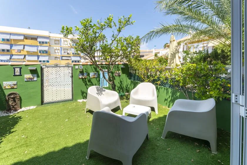 A small outdoor seating area with white chairs and a green lawn.