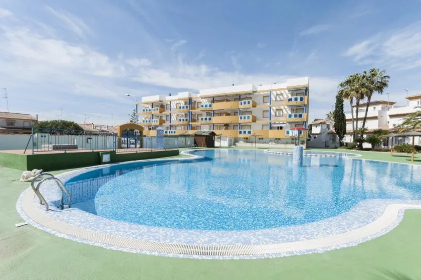 An outdoor swimming pool in front of a multi-story building.