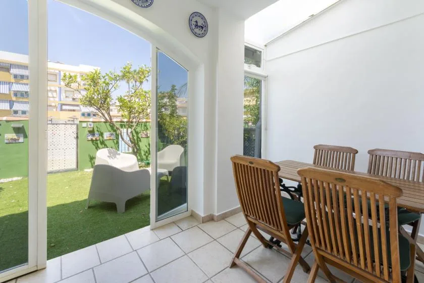 A dining area opens onto a small patio with a table and wooden seating.