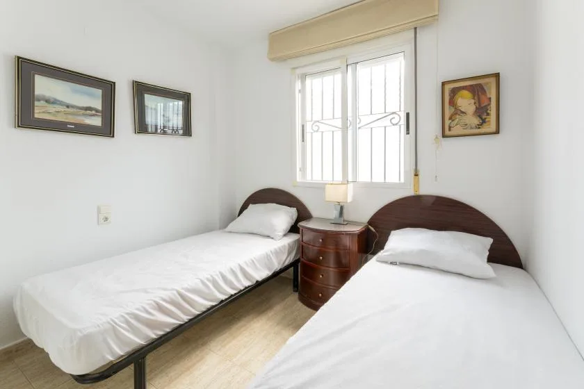 A twin bedroom with two single beds and a nightstand beneath a window.
