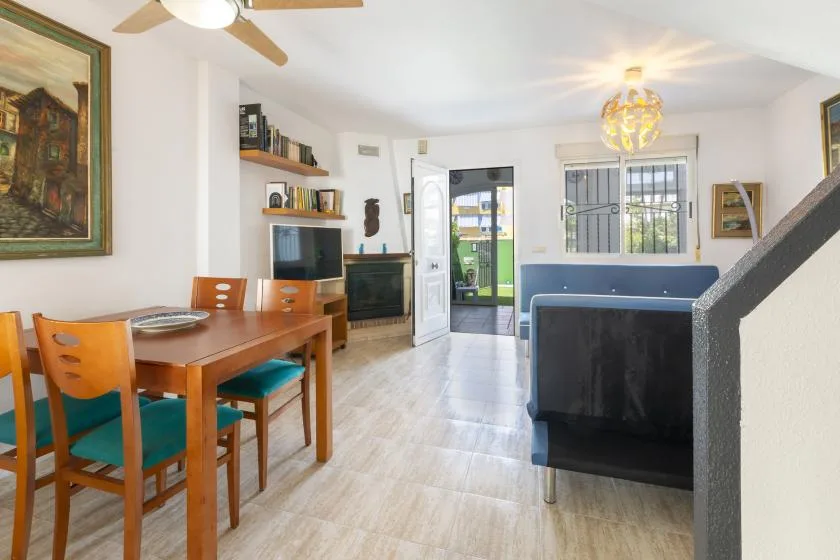 A dining and living area with a wooden table, seating, and a television.