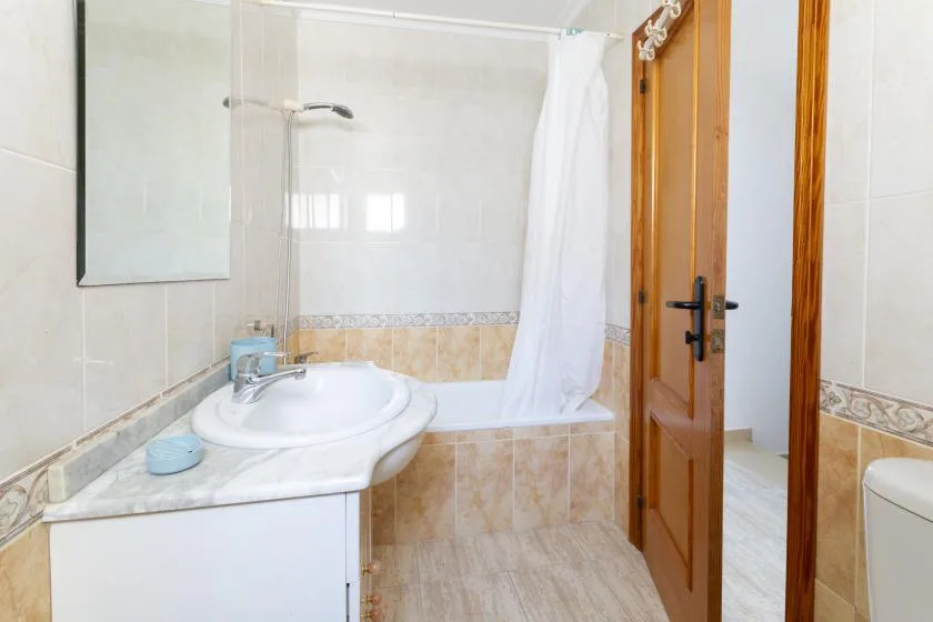 A tiled bathroom with a sink, bathtub, and shower curtain.