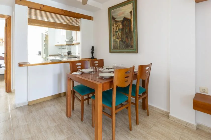 A dining area with a wooden table and chairs beside an open kitchen.