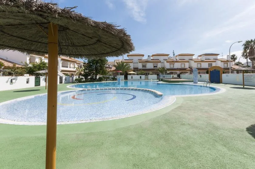 A swimming pool sits in an open courtyard surrounded by low-rise buildings.
