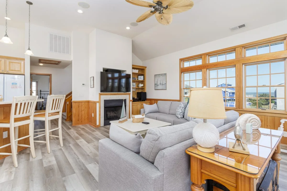 A bright living room with a gray seating area beside large windows.