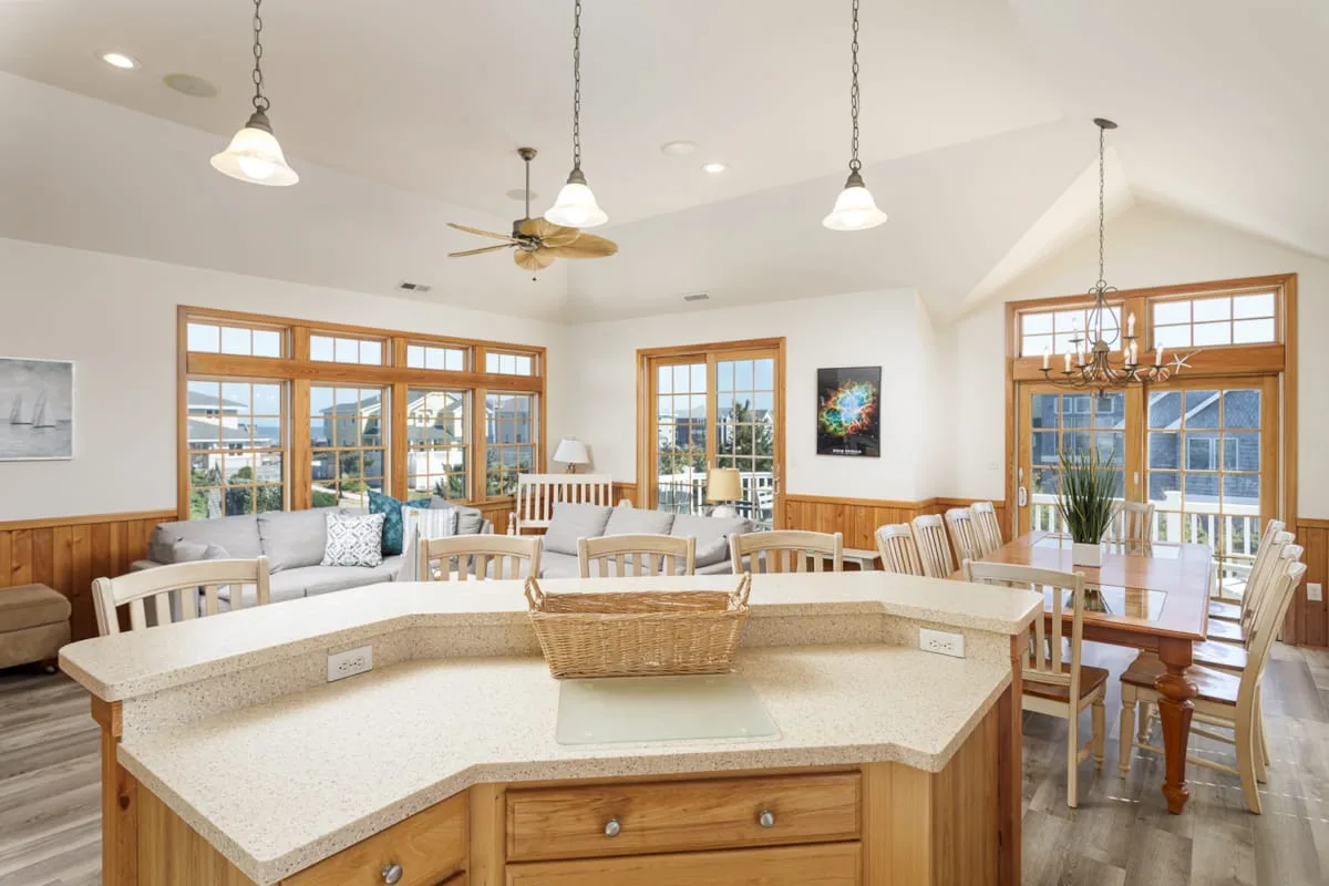 A bright open dining and kitchen area with a large island and windows.