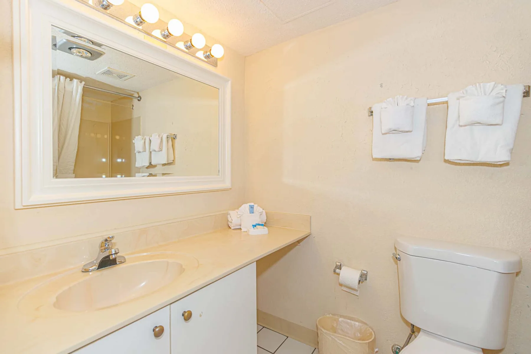A bathroom vanity with a sink and mirror sits beside a toilet.