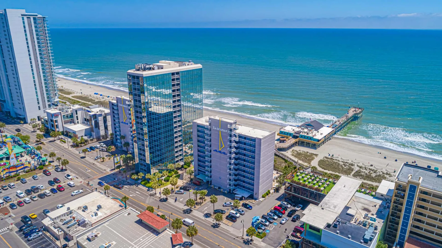 Aerial view of beachfront high-rises along a sandy shore and turquoise water.