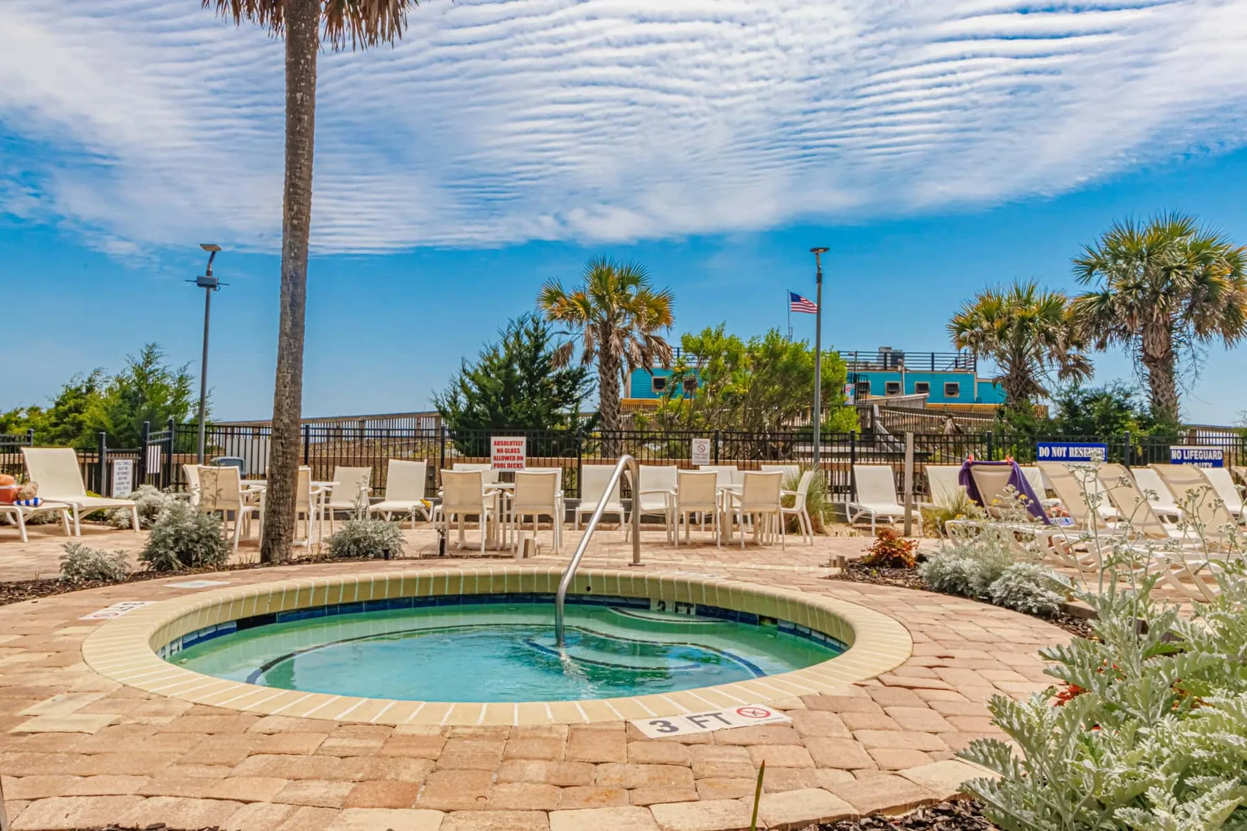 Outdoor pool area with a circular pool surrounded by lounge seating and palm trees.