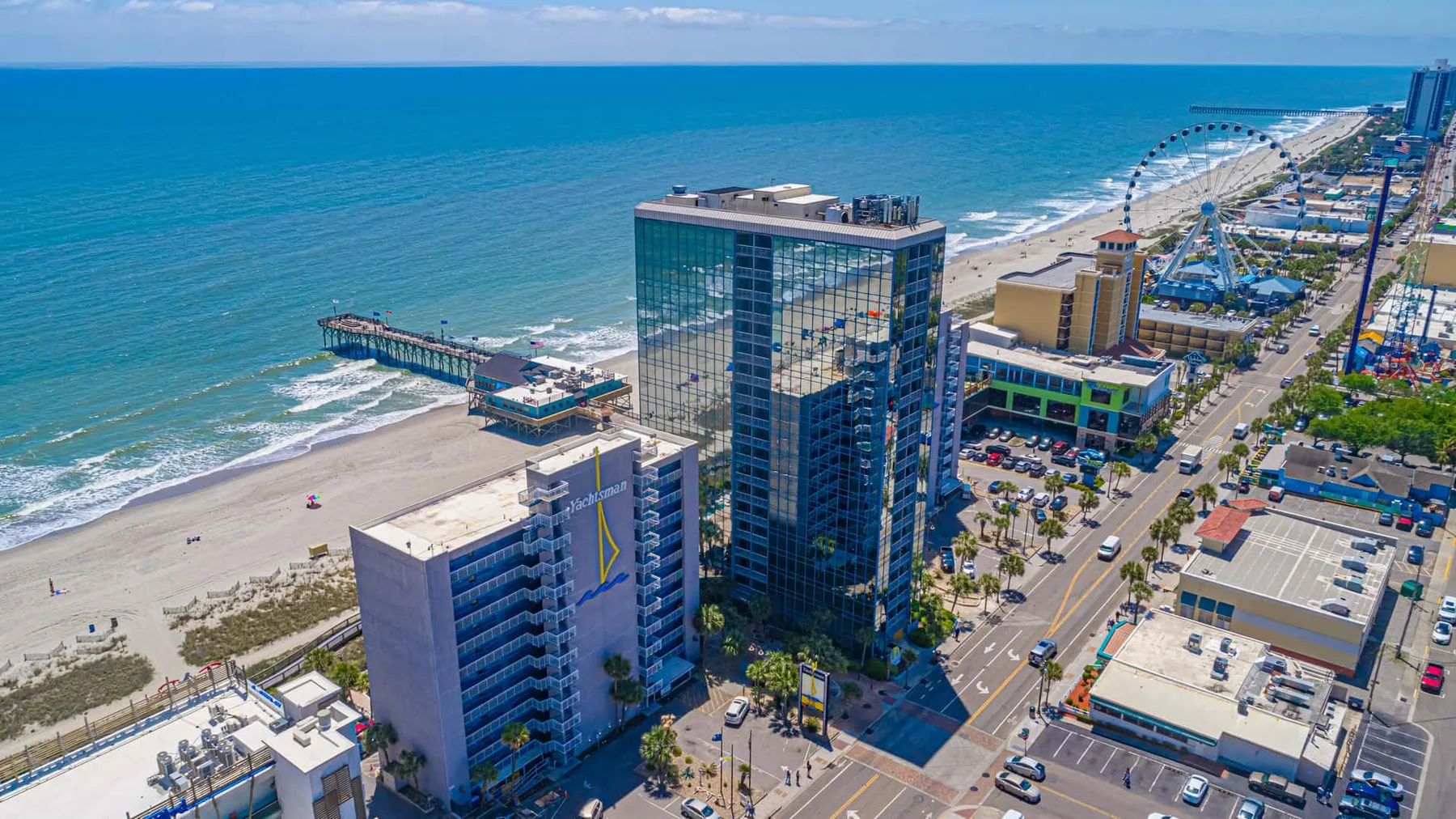 Aerial view of beachfront buildings along the ocean and a coastal road.