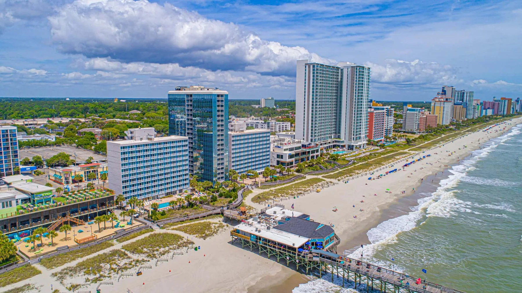 Aerial view of a beachfront city, with high-rise buildings lining the sandy shore.