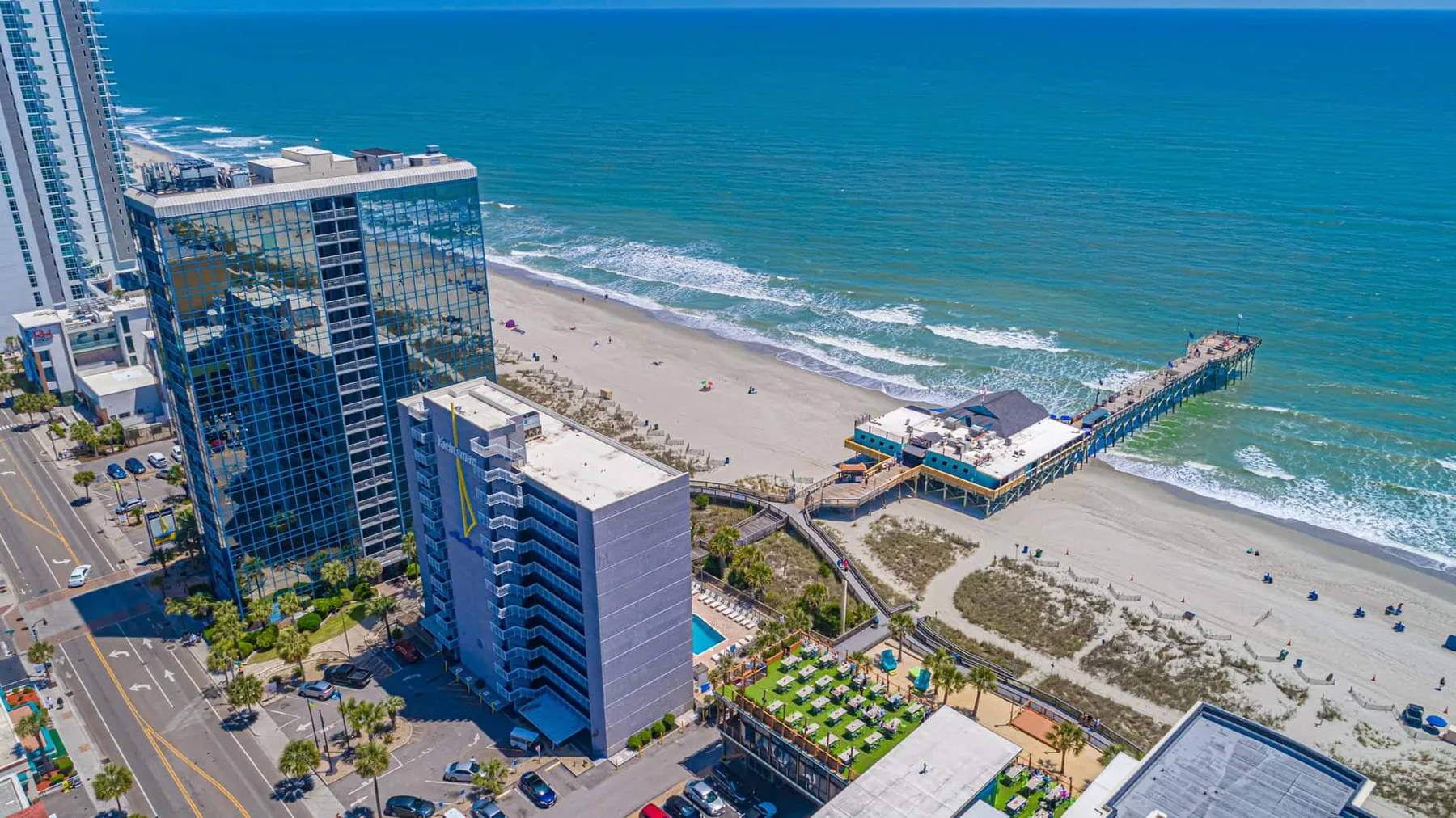 Aerial view of a beachfront with high-rise buildings and a pier.