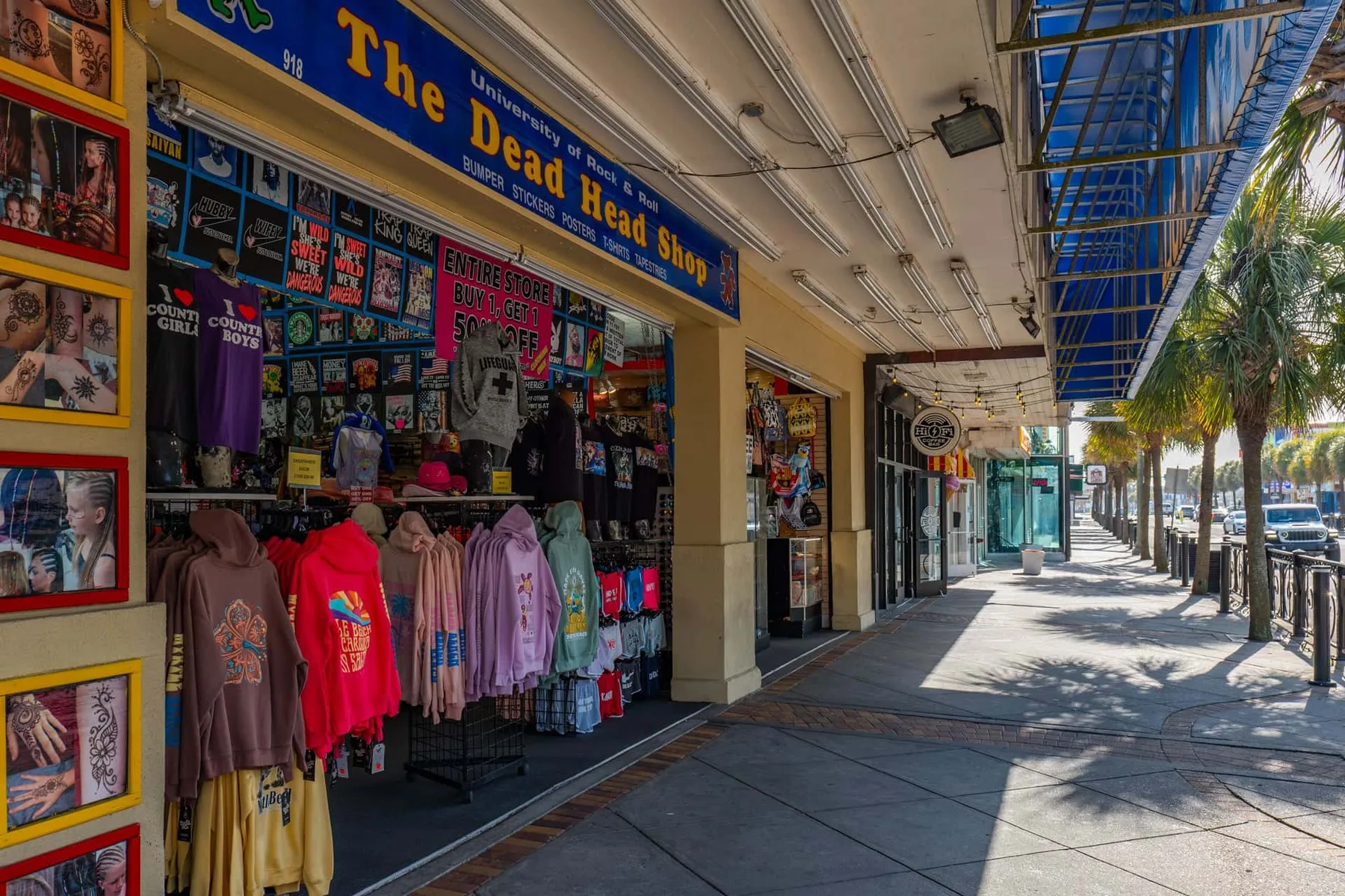 A souvenir shop displays colorful clothing and merchandise along a covered sidewalk.