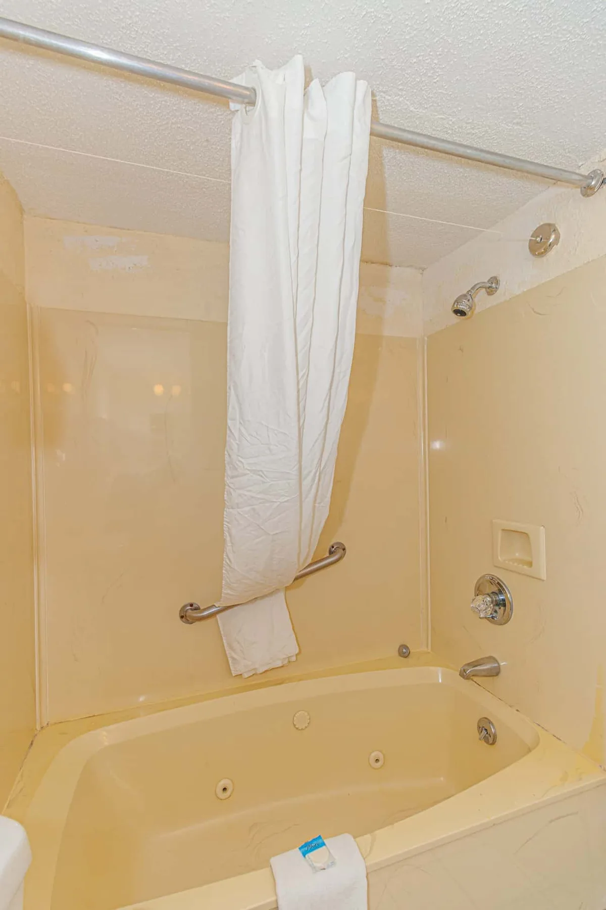A bathtub with a white shower curtain hanging above it.