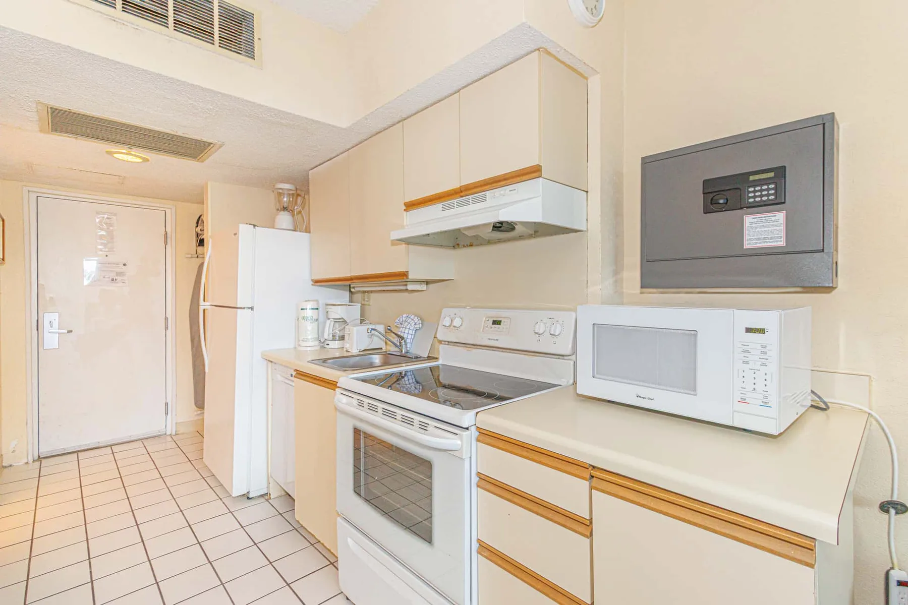 A compact kitchen with light cabinets, a stove, and a microwave.
