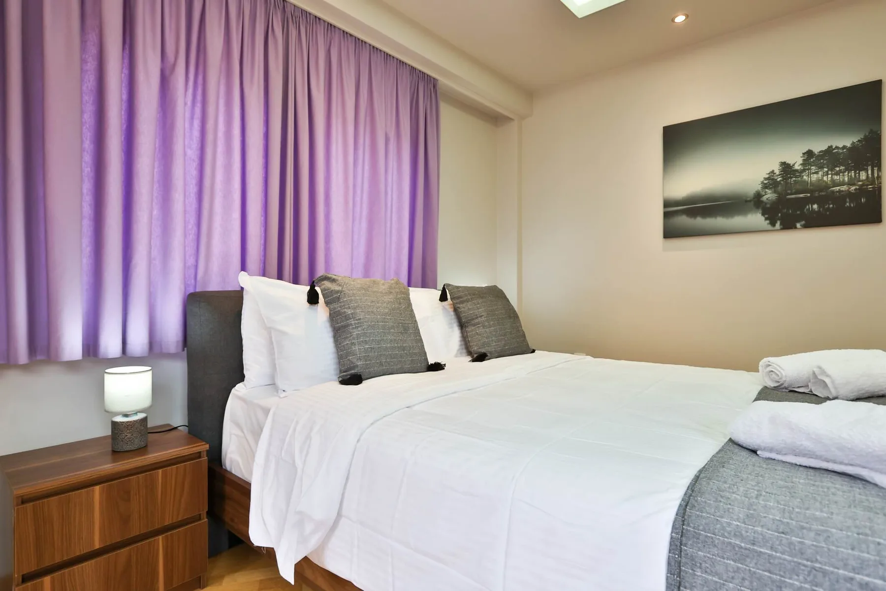 Un dormitorio con una cama bien hecha y cortinas moradas.