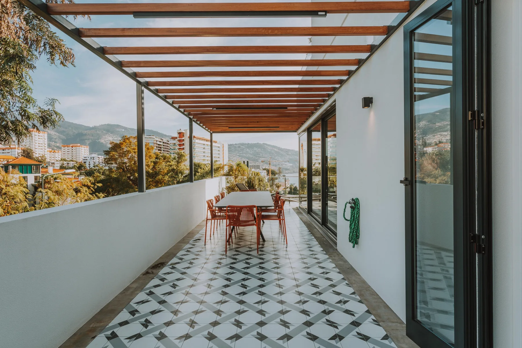 Una terraza cubierta con una mesa de comedor ofrece vistas de la ciudad y las colinas.
