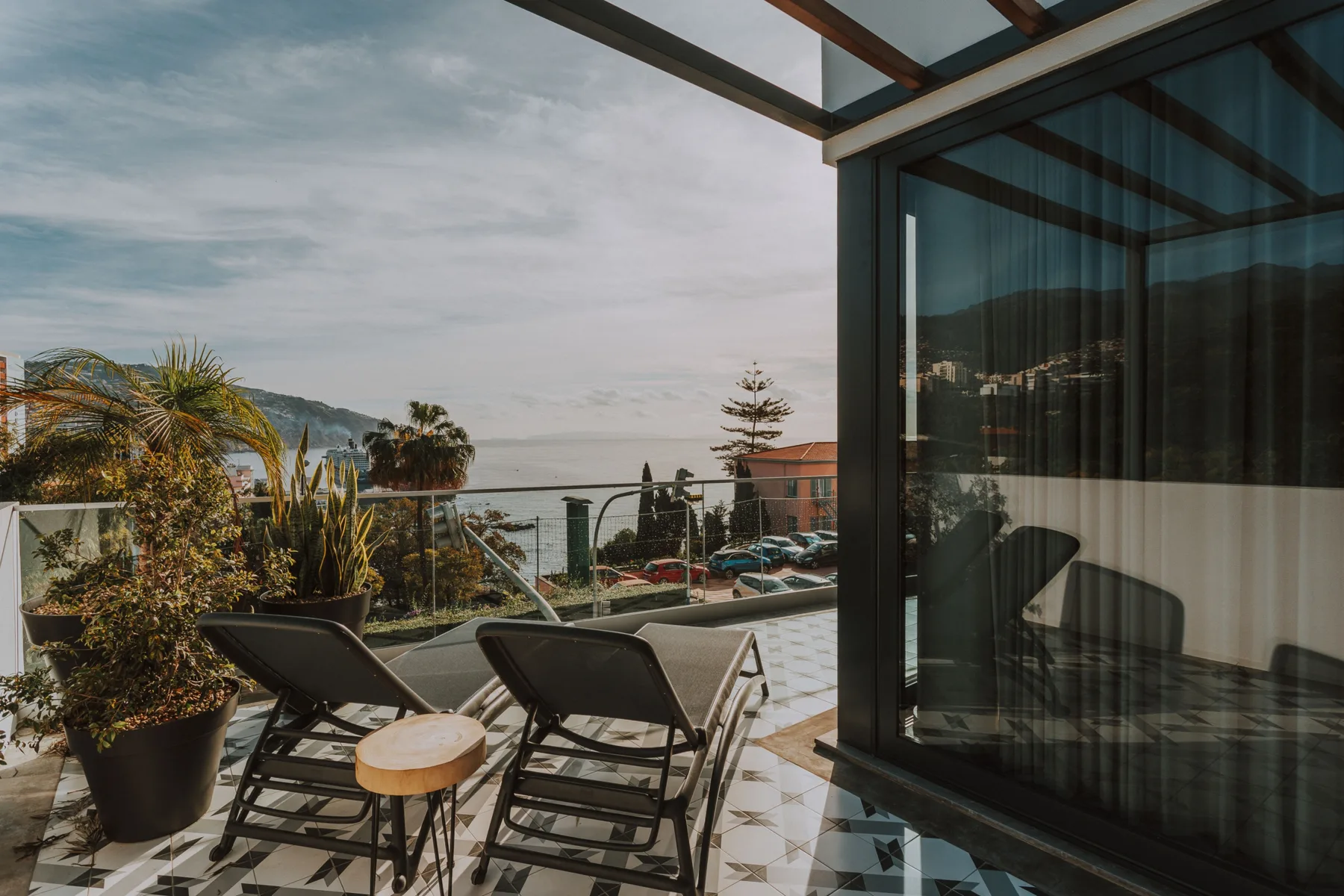 Una terraza amueblada con asientos da al mar y a edificios cercanos.