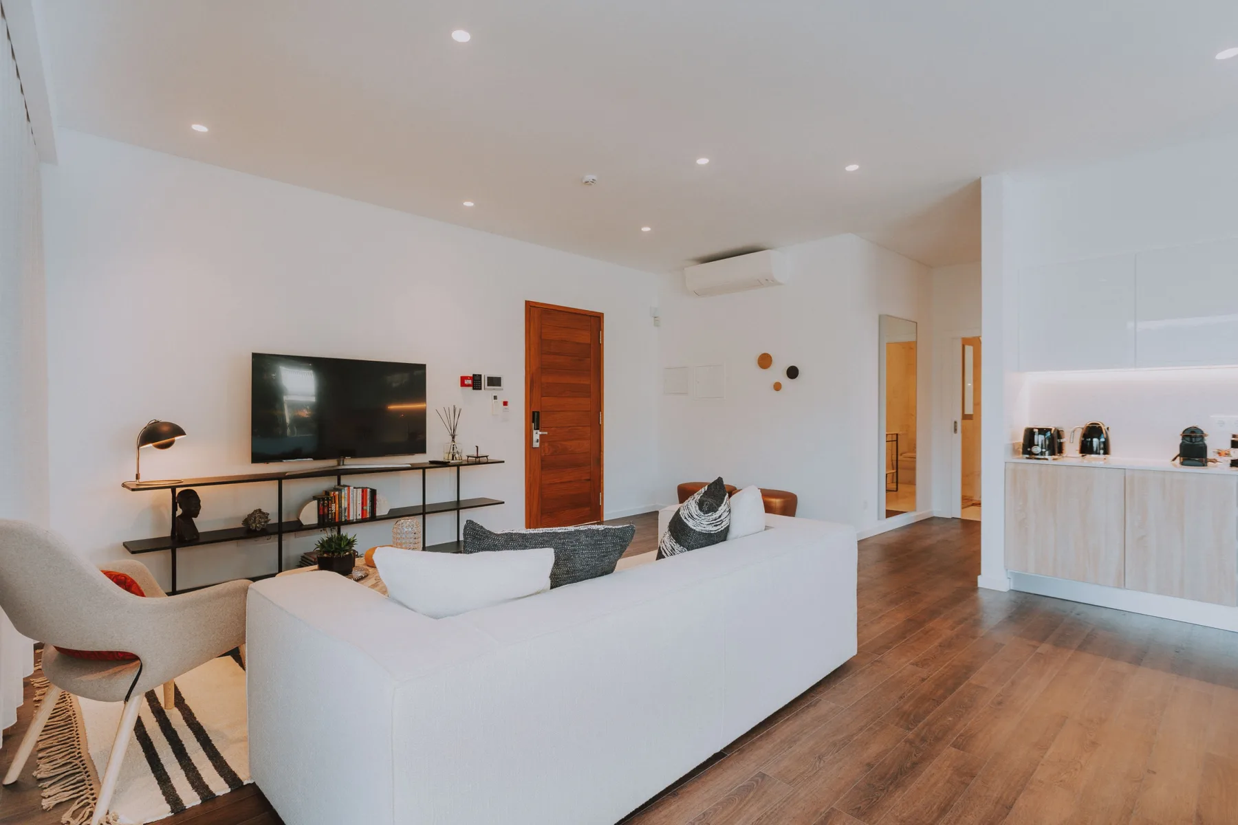 Una sala de estar luminosa con asientos, un televisor y suelo de madera.