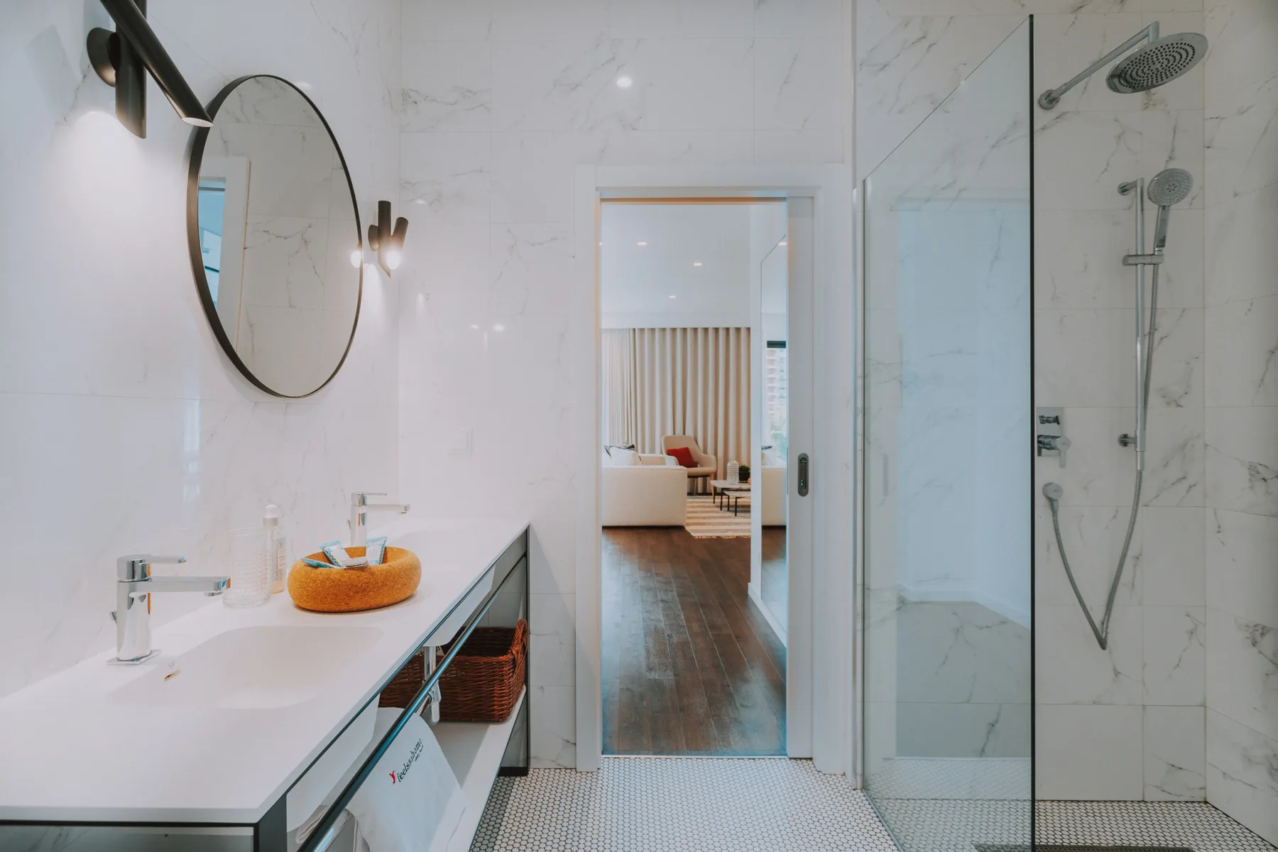 Un baño luminoso con un lavabo largo y una ducha de cristal.