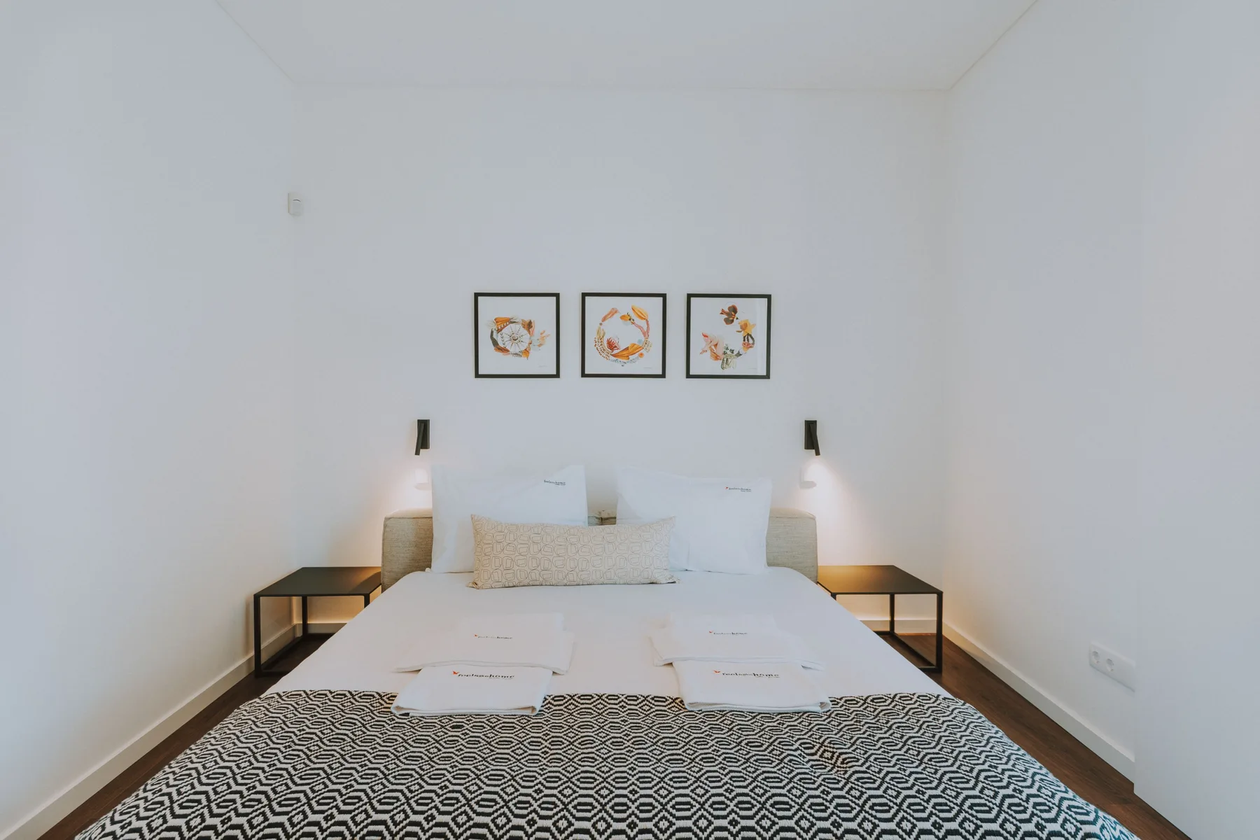 Un dormitorio con la cama arreglada y tres cuadros en la pared.