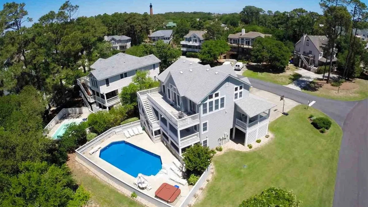 Vista aérea de una casa grande con piscina y árboles alrededor.