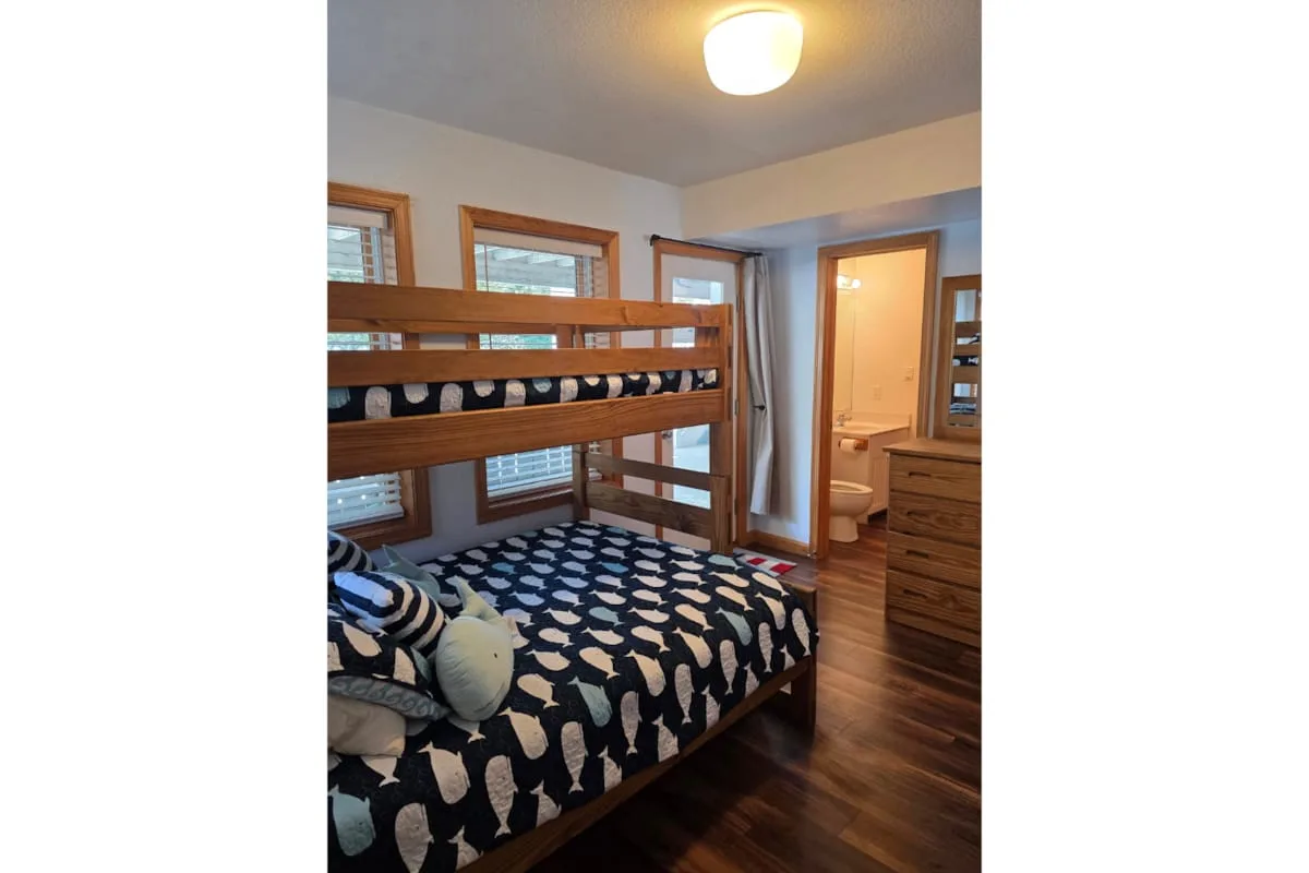 Un dormitorio con una litera de madera y ropa de cama estampada.