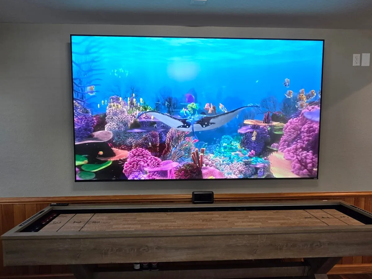 Una sala de juegos tiene una mesa de billar frente a una pantalla grande con una escena submarina.