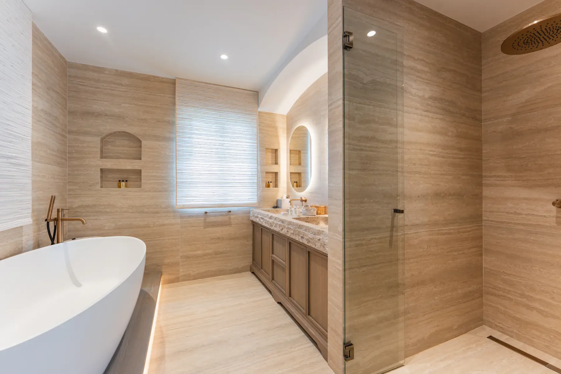 Un baño luminoso con bañera, lavabo y ducha de cristal.