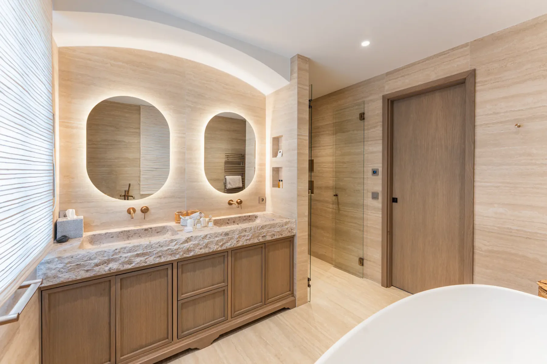 Un baño con dos espejos sobre un tocador largo y armarios de madera.