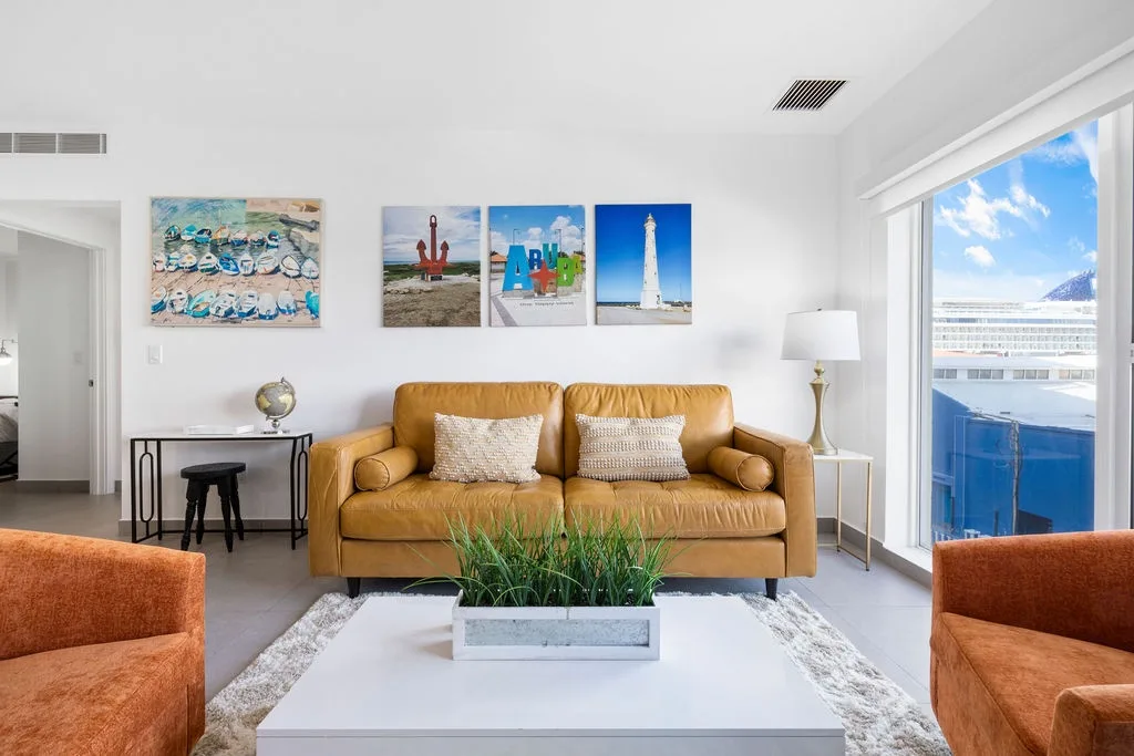 Unwind in your bright living room with tan leather sofa and coastal artwork while ocean views greet you through open patio doors.