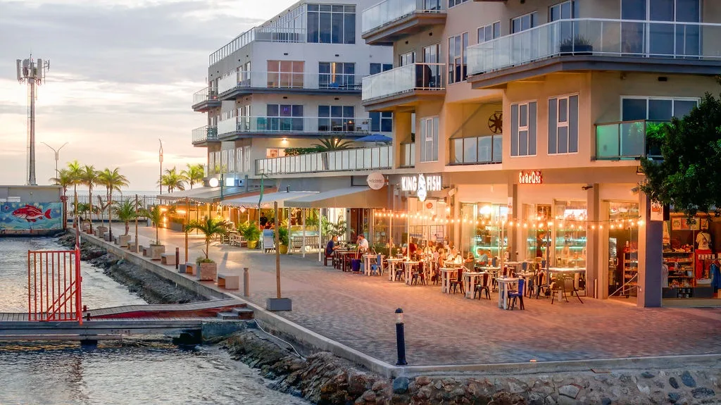 Modern waterfront property featuring apartments and ground-level dining, steps from the marina and surrounded by restaurants and shops.