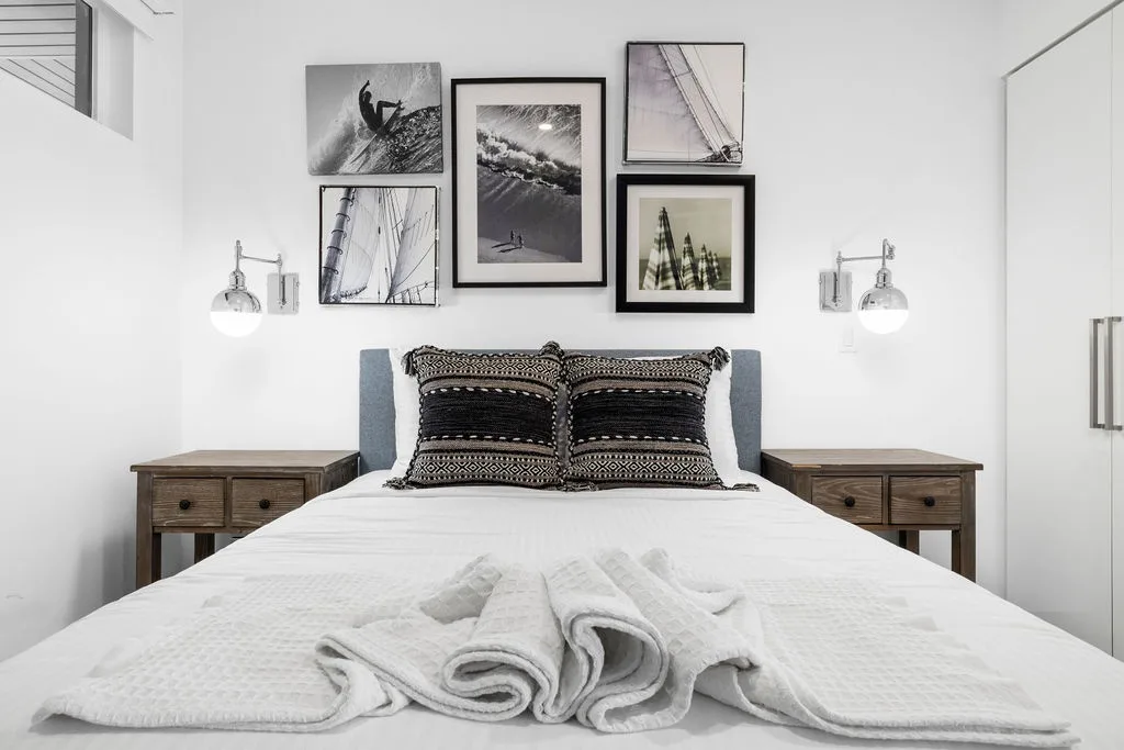 Sink into crisp white linens and plush towels in your restful bedroom, where coastal artwork and warm lighting create your personal sanctuary.