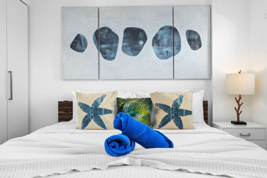 Your coastal retreat awaits: plush bedding, beachy art, and fresh towels welcome you to unwind in serene comfort.