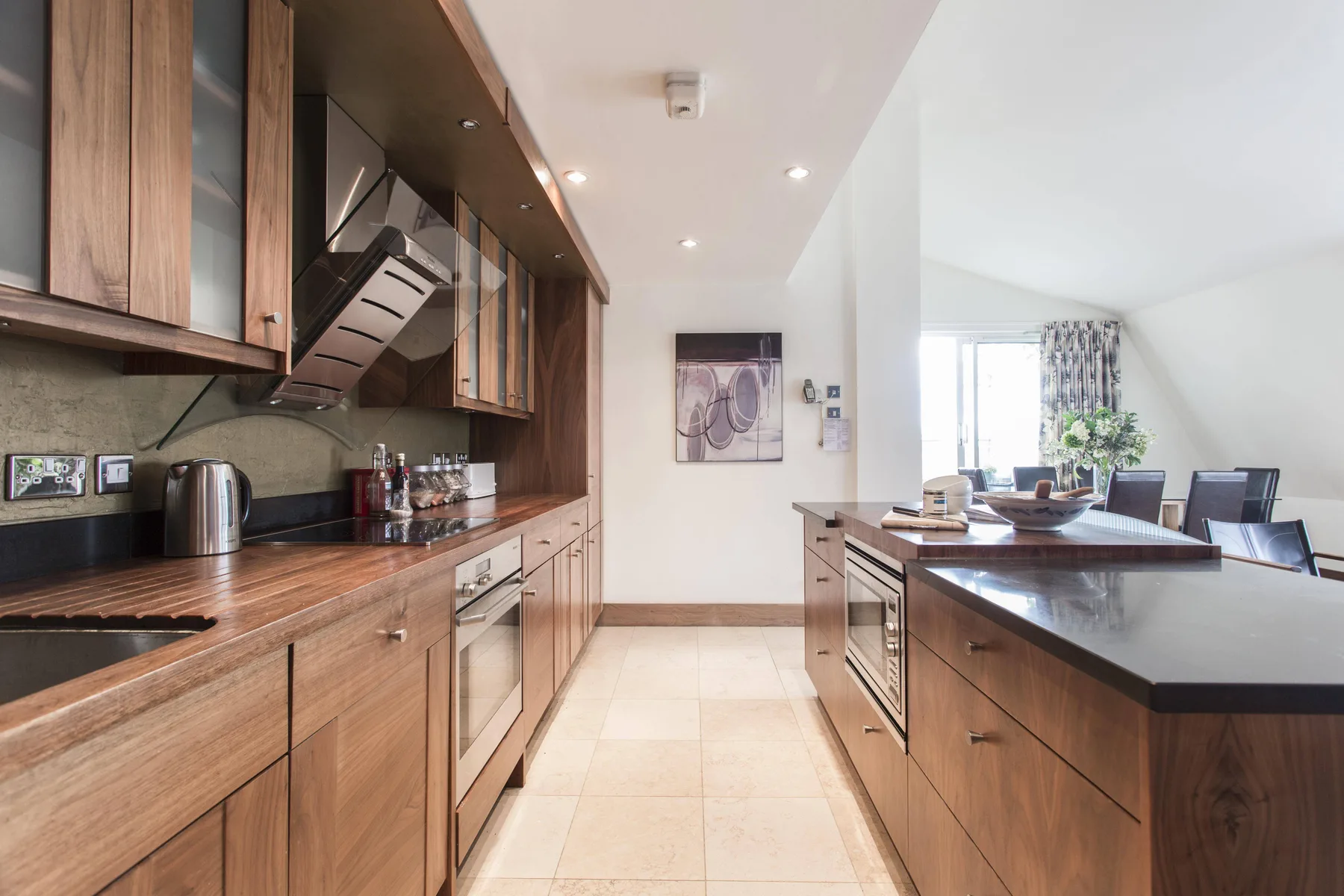 Una cocina moderna con gabinetes de madera, una isla central y un comedor contiguo.