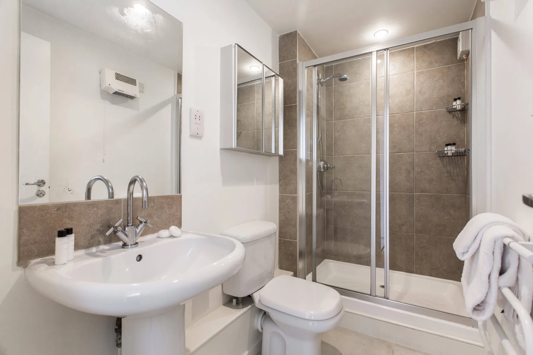 Un baño con lavabo, inodoro y ducha con mampara de vidrio.