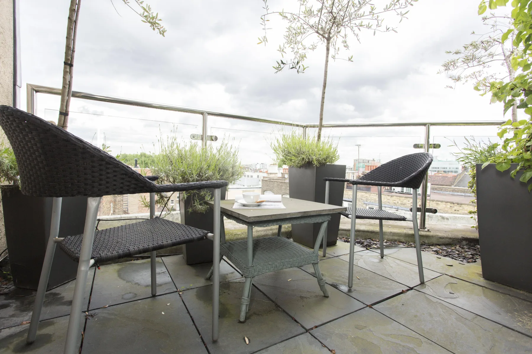 Una zona de terraza con asientos, una mesa baja y plantas en macetas.