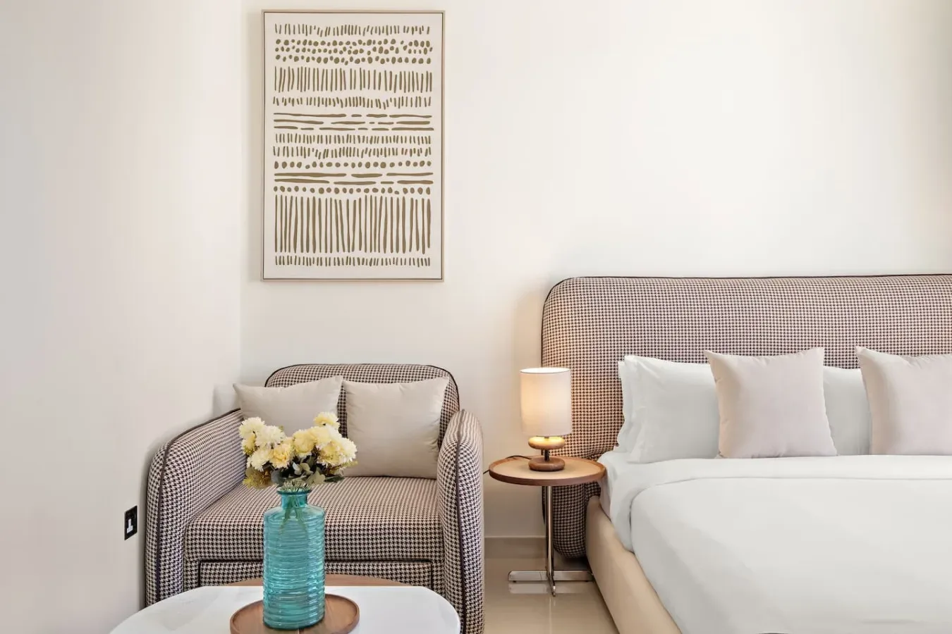 Un dormitorio con una cama, un sillón tapizado y una mesita de noche.
