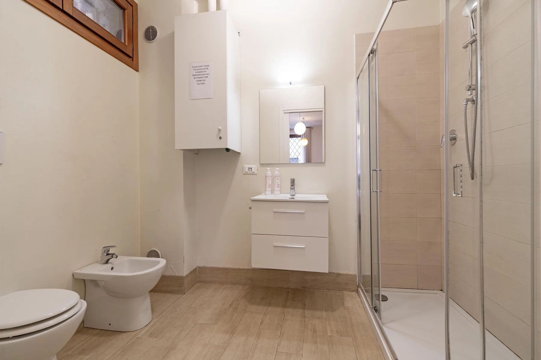 Un baño con lavabo, inodoro y ducha con mampara de vidrio.