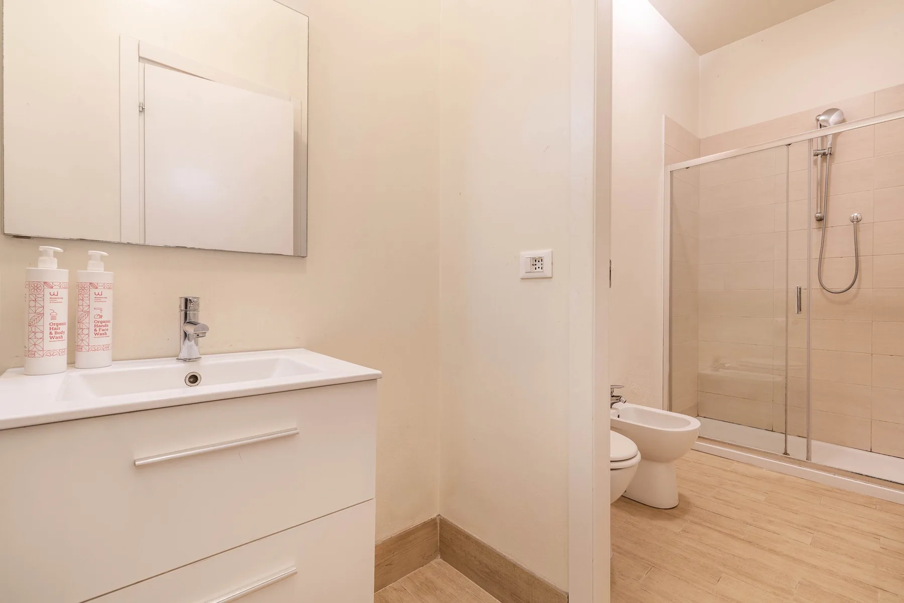 Un baño con lavabo, espejo y ducha con mampara de vidrio.