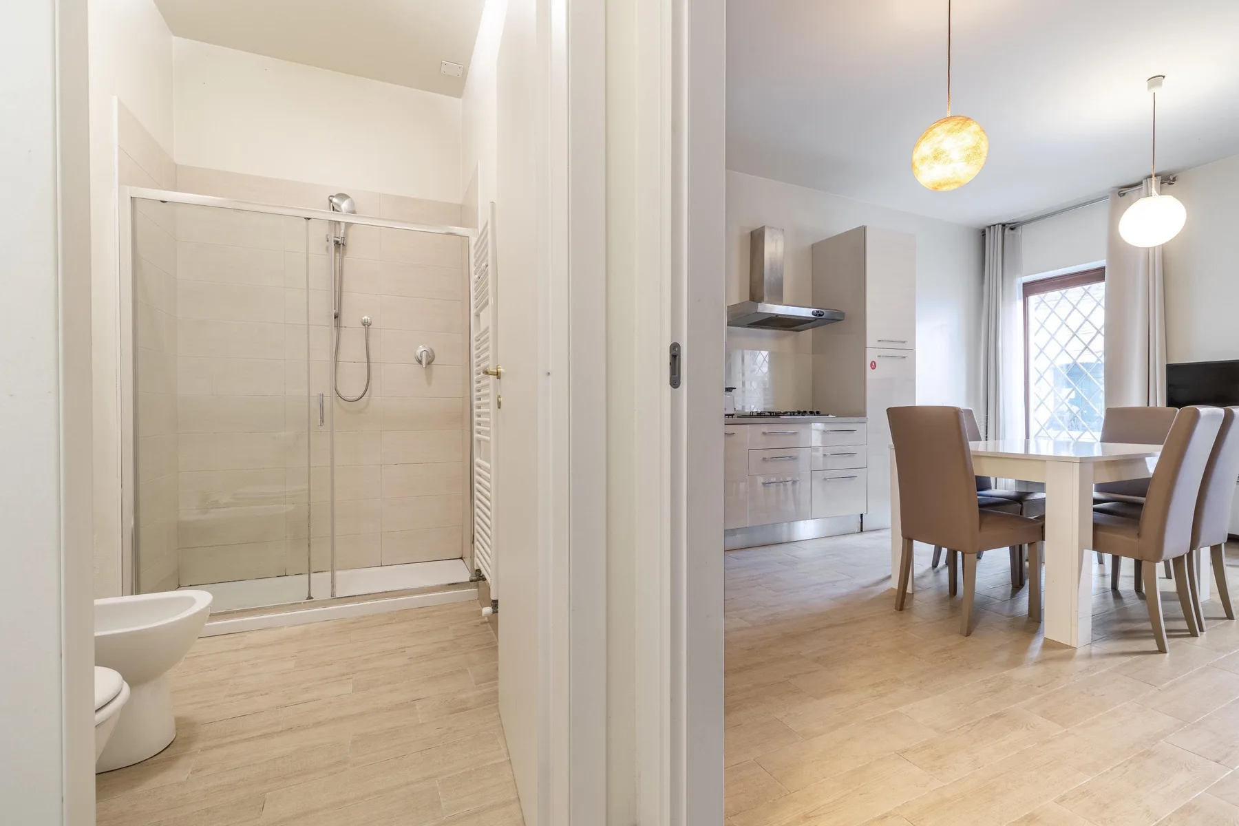 Un baño con ducha se abre a una zona de comedor con una mesa.