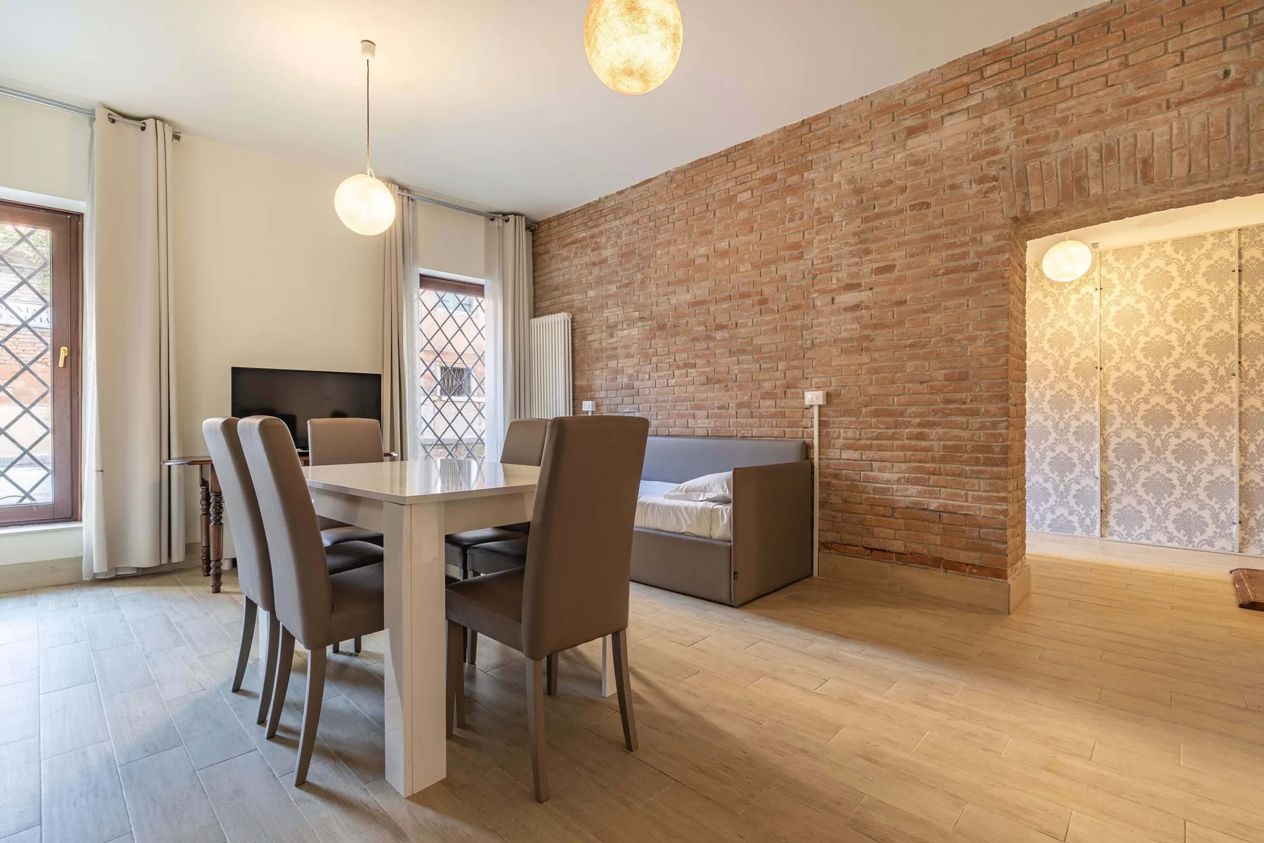Comedor con mesa y sillas junto a una pared de ladrillo.