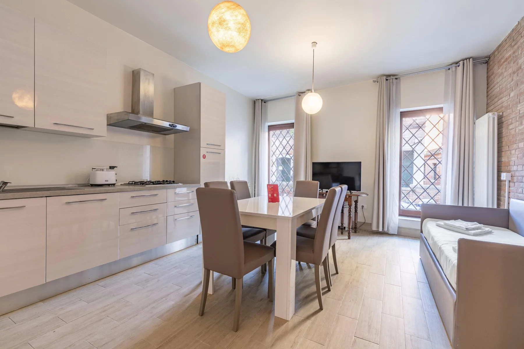 Una luminosa cocina abierta con comedor y una mesa junto a ventanas altas.
