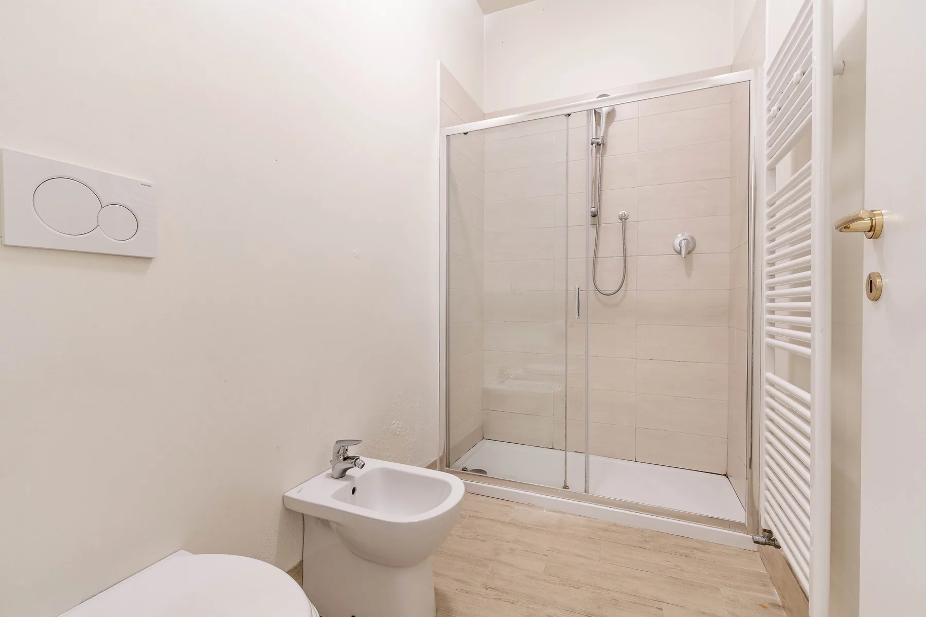 Un baño luminoso con ducha y lavabo de pared.