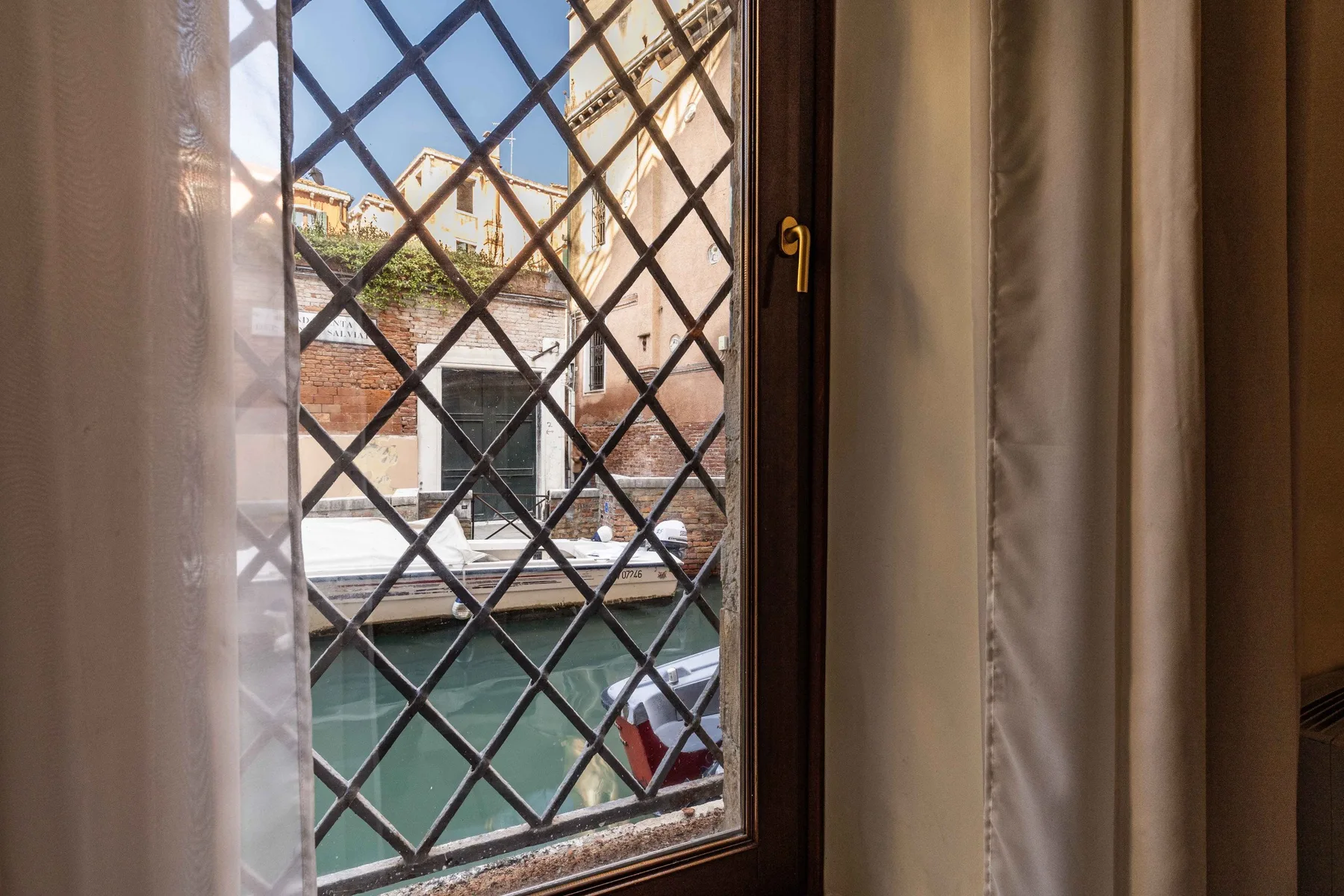 Una ventana da a un canal y a edificios al otro lado del agua.